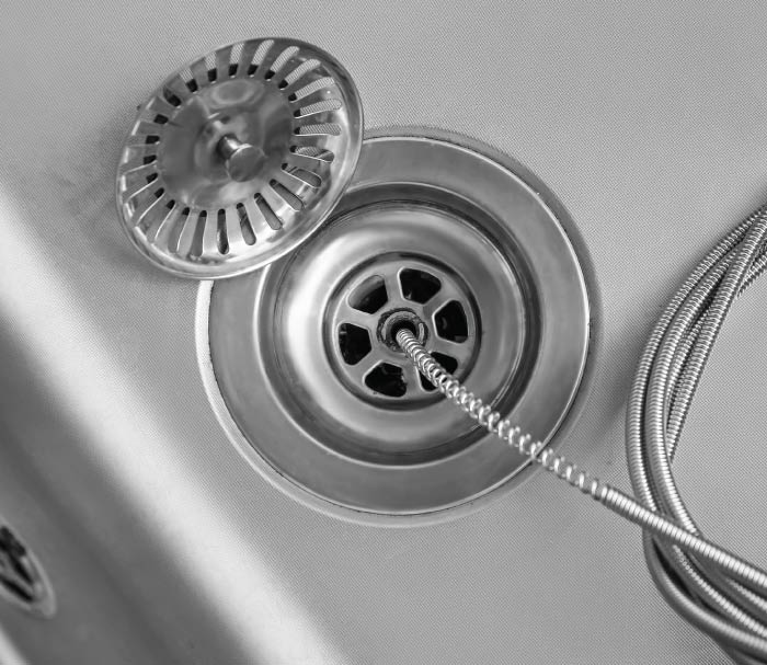 J&L plumber performing an expert drain cleaning service in a Sacramento home with professional equipment.